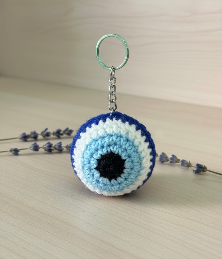 Crocheted keychain with blue and white circular design on a light surface.