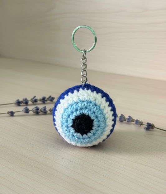Crocheted keychain with blue and white circular design on a light surface.